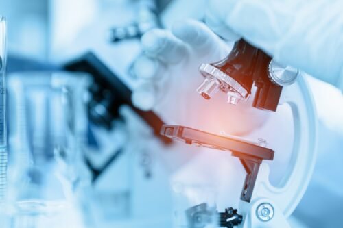 Close Up Scientist using microscope in laboratory room while mak