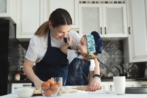Mother and daughter in matching aprons and chef’s hat cooking in